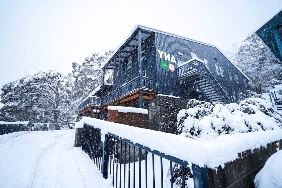YHA Thredbo lodge in heavy snowfall, with snow covering the building and surrounding landscape.
